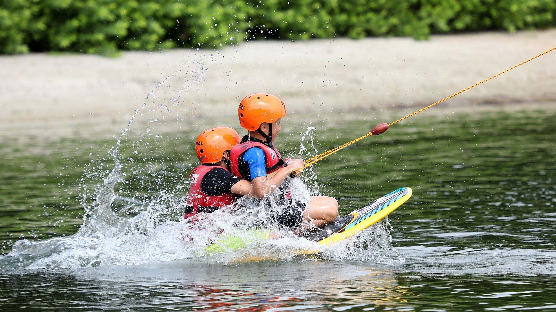 Ein Kind und ein Erwachsener auf einem Wakeboard
