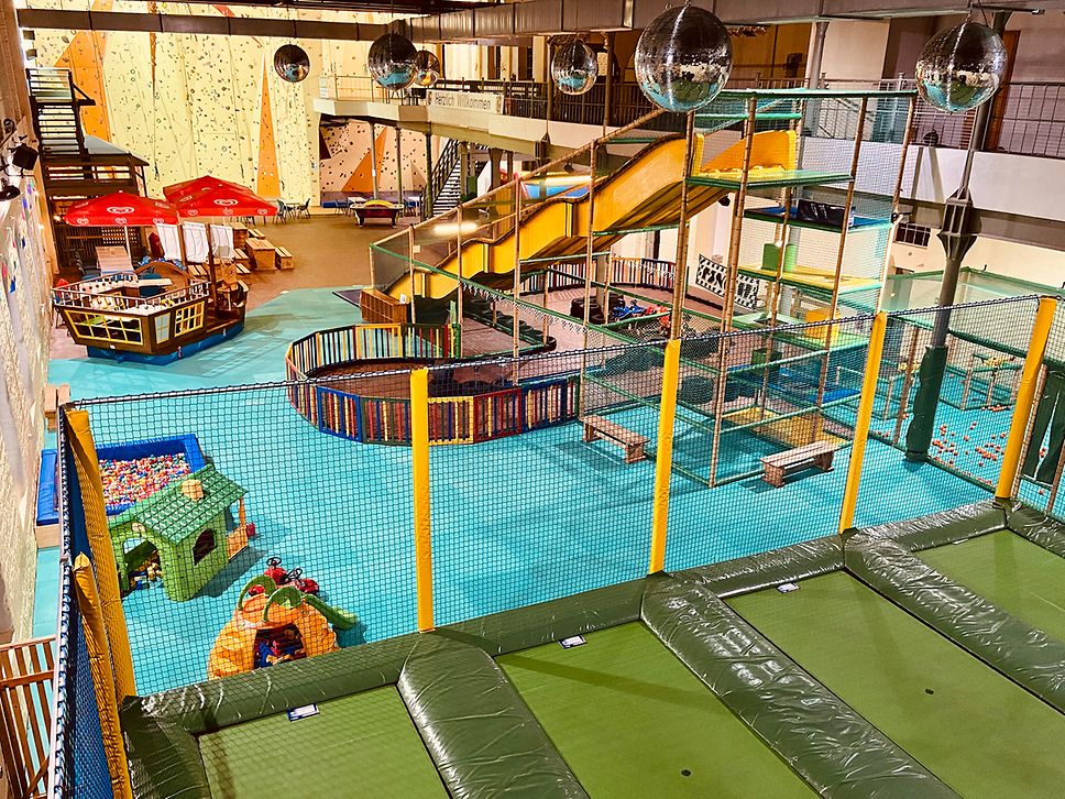 Blick auf den Indoor-Spielpark mit u.a. Trampolinen, Rutsche und Bällebad.