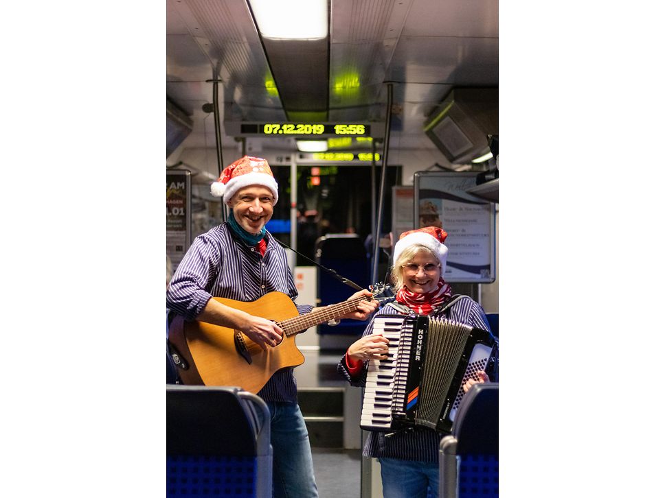 Zwei Musiker spielen mit Akkordeon und Gitarre im Zug Advents- und Weihnachtslieder 