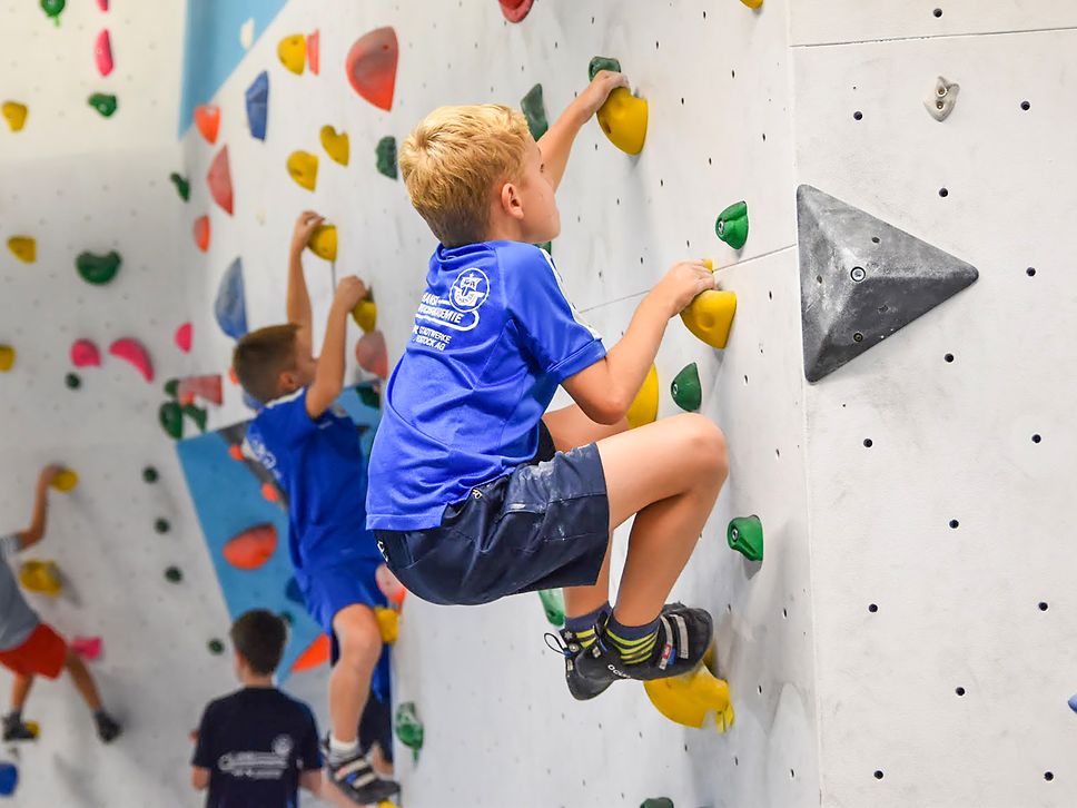 Kinder klettern konzentriert an einer Kletterwand in der Boulderhalle "Felshelden" in Warnemünde.