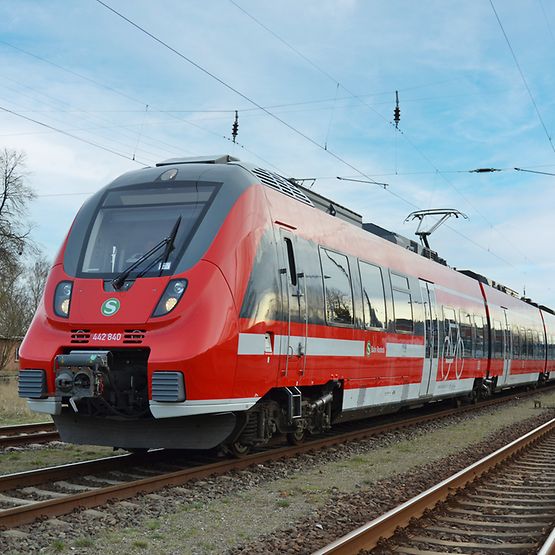 Ein rot-weißer Zug der Baureihe 442 in der Landschaft
