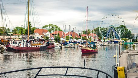 Segelboote auf dem Fluss Ryck, im Hintergrund ein Riesenrad und die Flaniermeile 