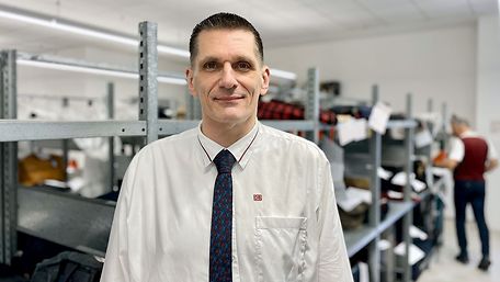 Portrait von Peter Achtmann vor den gefüllten Regalen der DB Fundstelle Lichtenberg