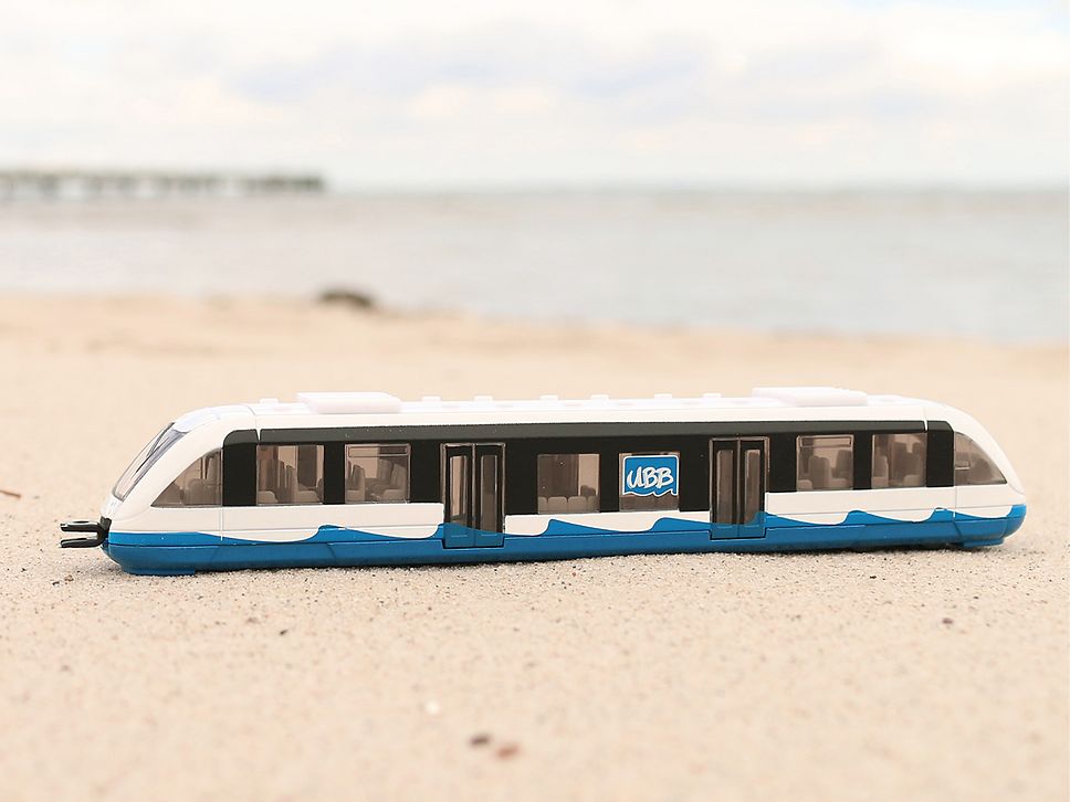 Miniaturmodell eines UBB-Triebwagens steht am Strand im Sand