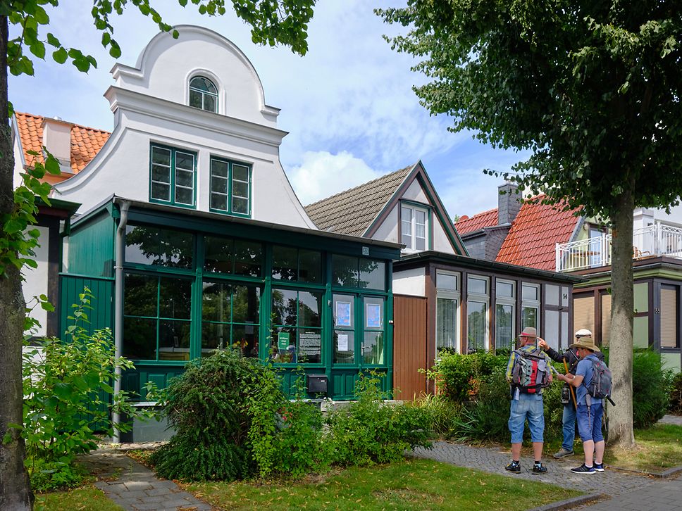 Drei Männer mit Rucksäcken vor dem Edvard-Munch-Haus in Warnemünde