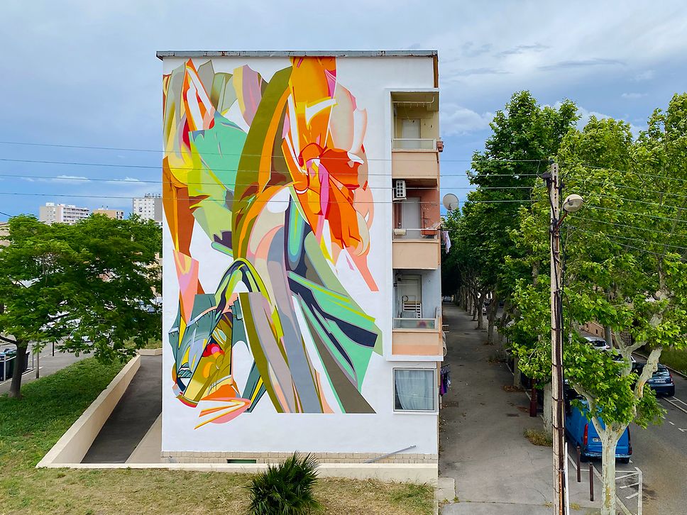 Eine bunt bemalte Hauswand eines dreistöckigen Hauses an einer kleinen Straße