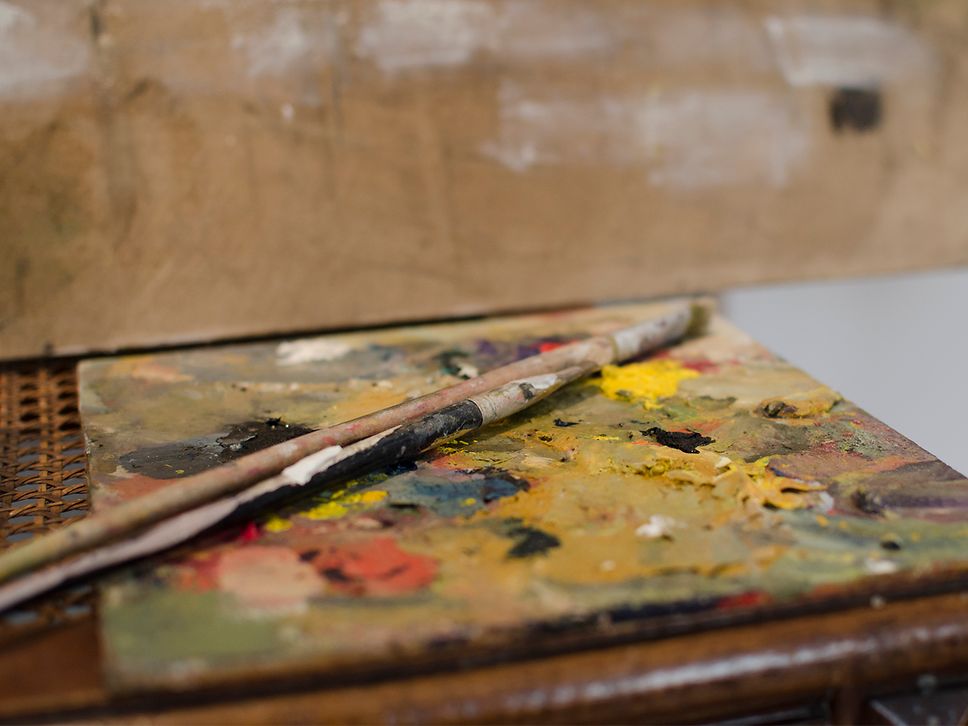 Farben und Pinsel auf einer Holzpalette