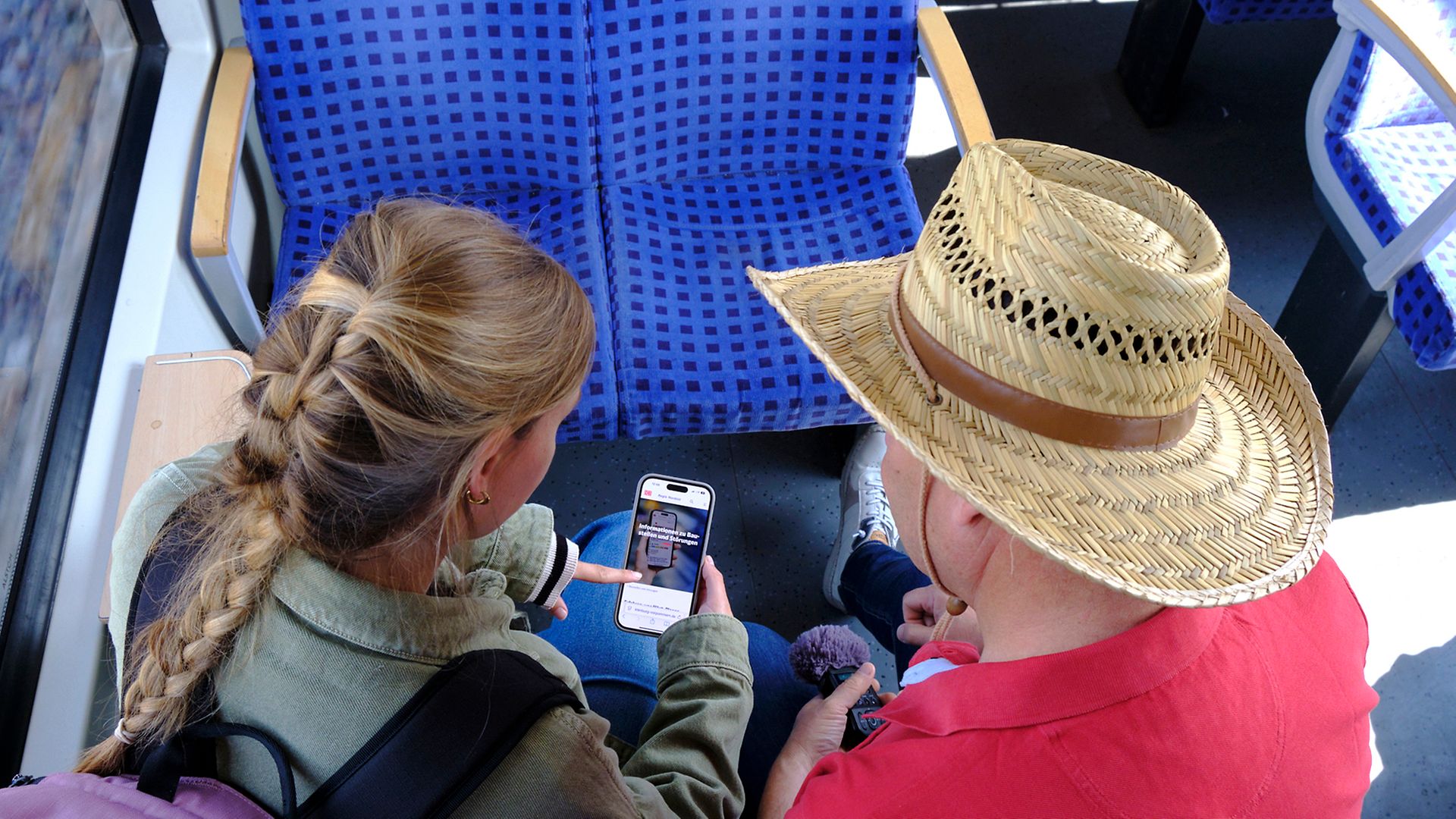Maike und Ingo schauen per Handy auf die Seiten der DB Regio Verkehrsinfo.