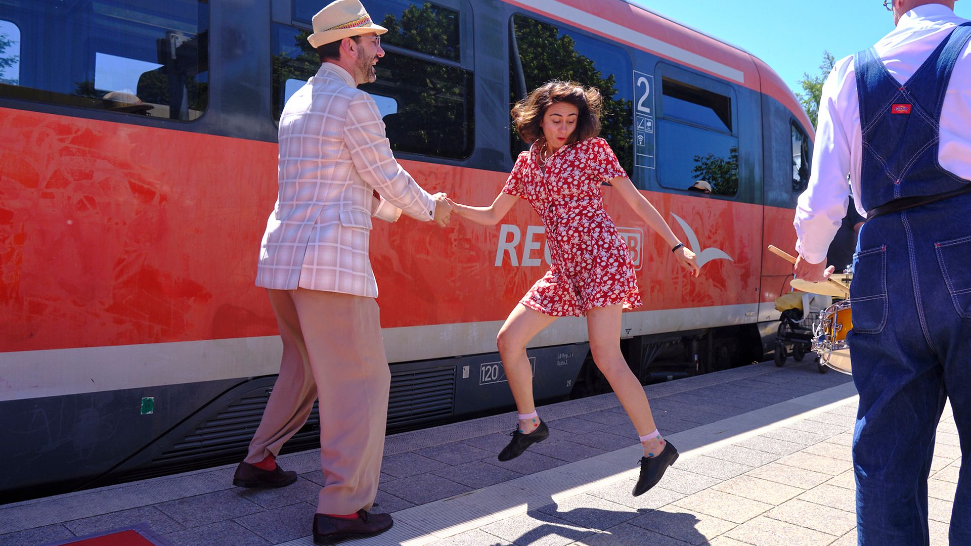Tanzendes Paar der Rostocker „Swing Connection“ vor Regionalzug am Bahnsteig in Graal-Müritz