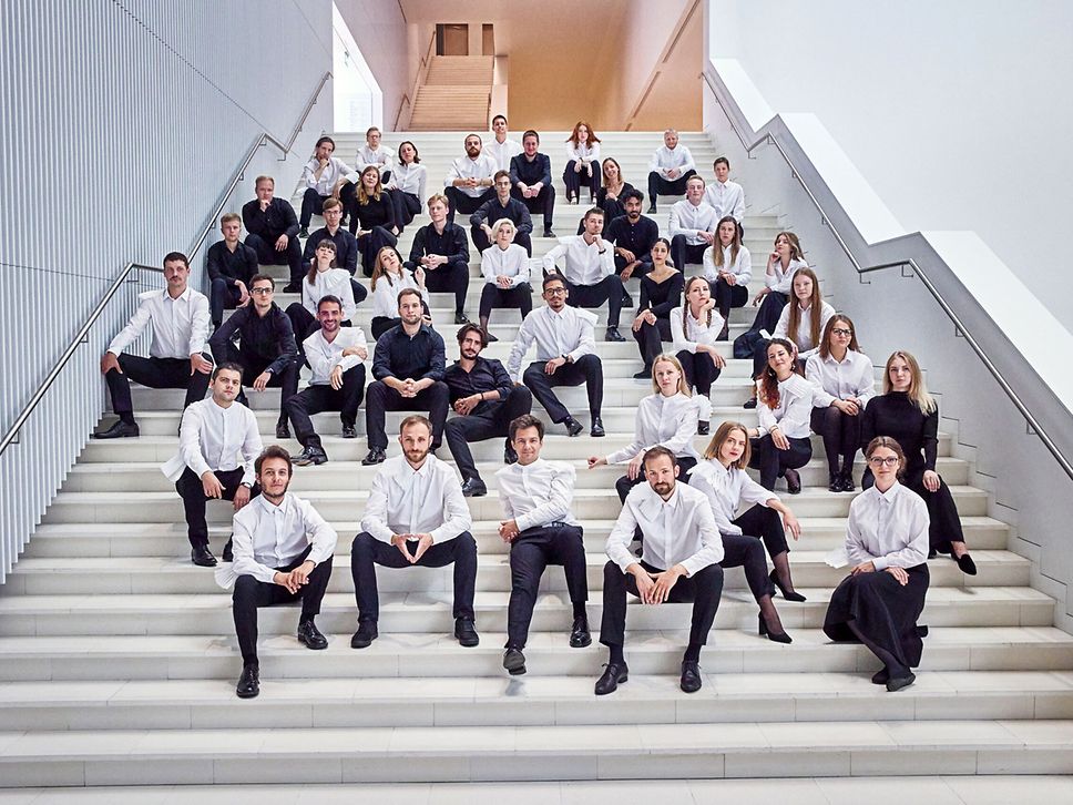 Die jungen Musikerinnen und Musiker des Orchesters Baltic Sea Philharmonic sitzen auf einer Treppe.