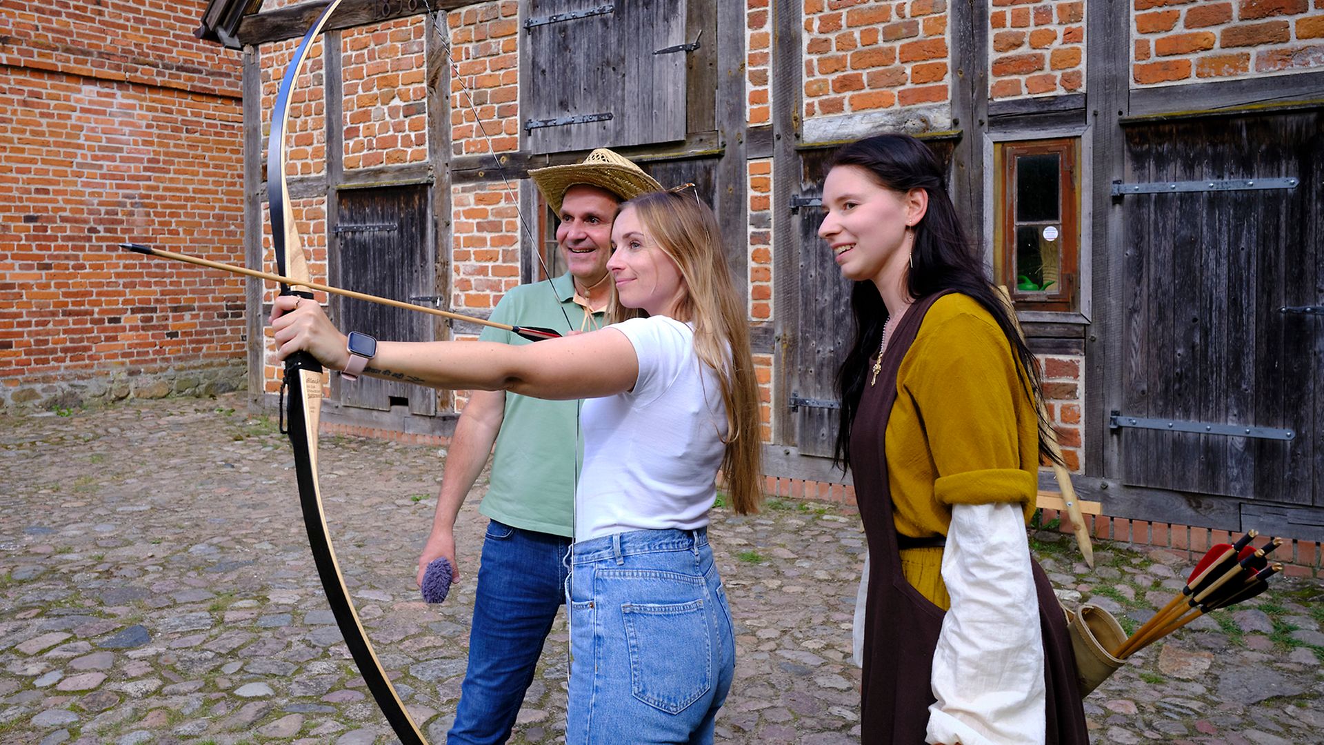 Maike Bäßler auf Burg Stargard mit Pfeil und Bogen, hinter ihr Ingo Ruff