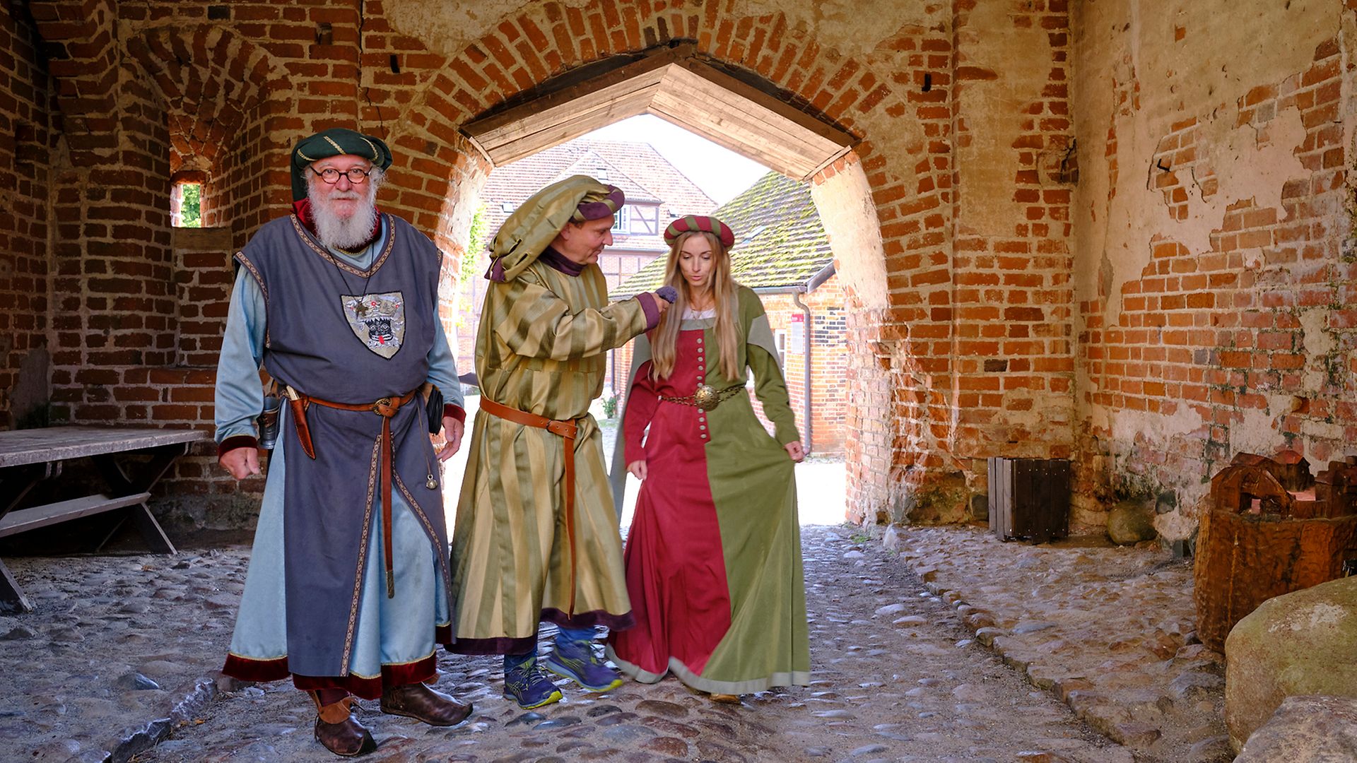 Museologe Frank Saß, Ingo Ruff und Maike Bäßler in historischen Kostümen vor dem Burgtor auf Burg Stargard