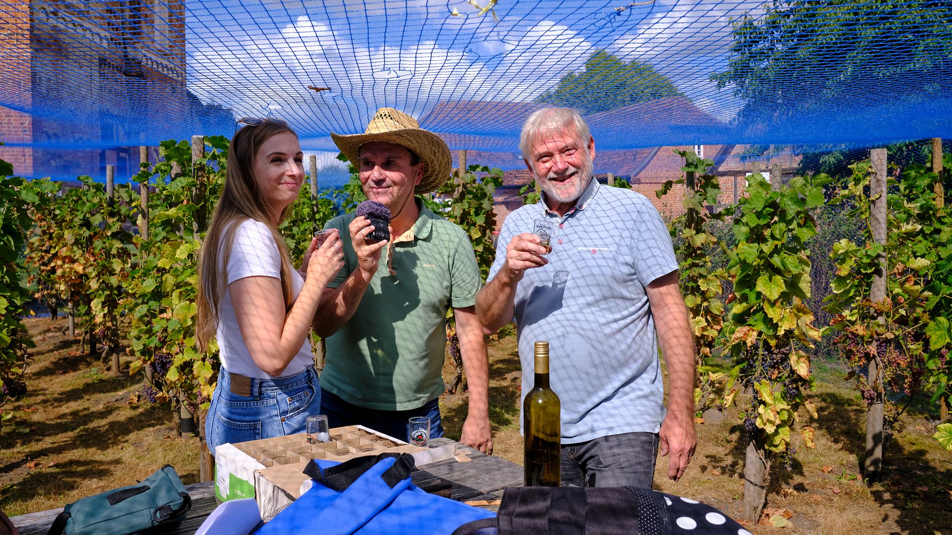 Podcastteam Maike Bäßler und Ingo Ruff mit Stefan Schmidt vom Winzerverein zu Burg Stargard bei der Weinprobe auf dem Weinberg