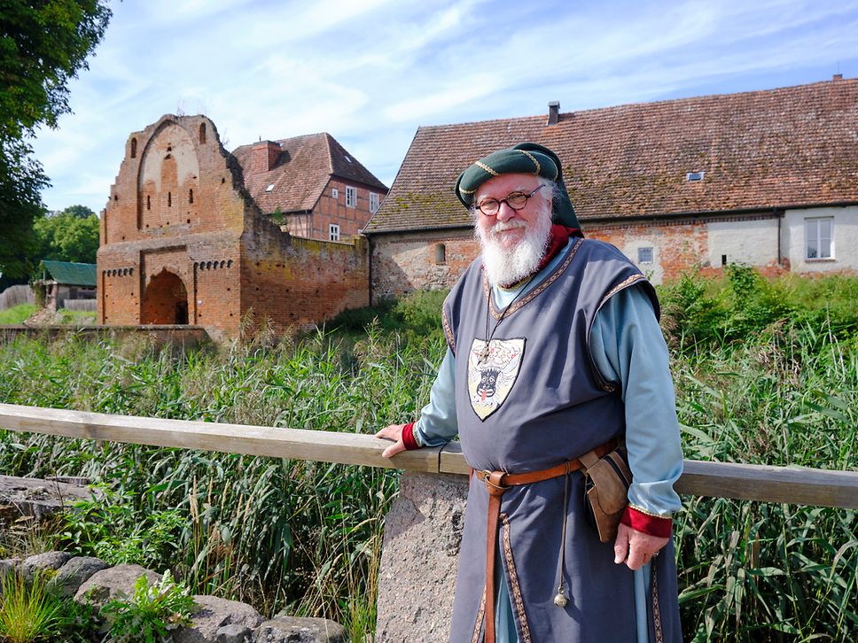Museologe Frank Saß im historischen Gewand vor dem Burggelände