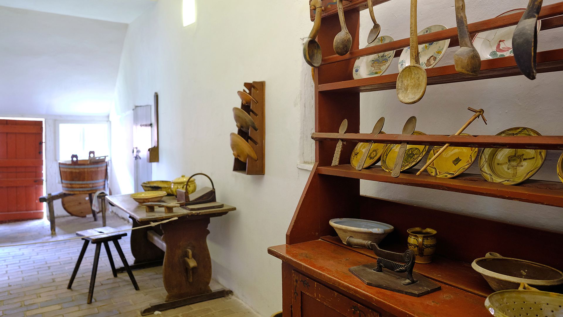 Hölzerne Löffel und traditionelle Teller eines Bauernhaushalts im Regal