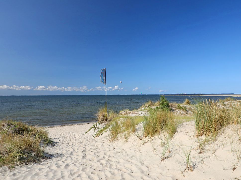 Ein Sandweg führt durch die Dünen zur Ostsee unterm blauen Himmel im Seebad Lubmin