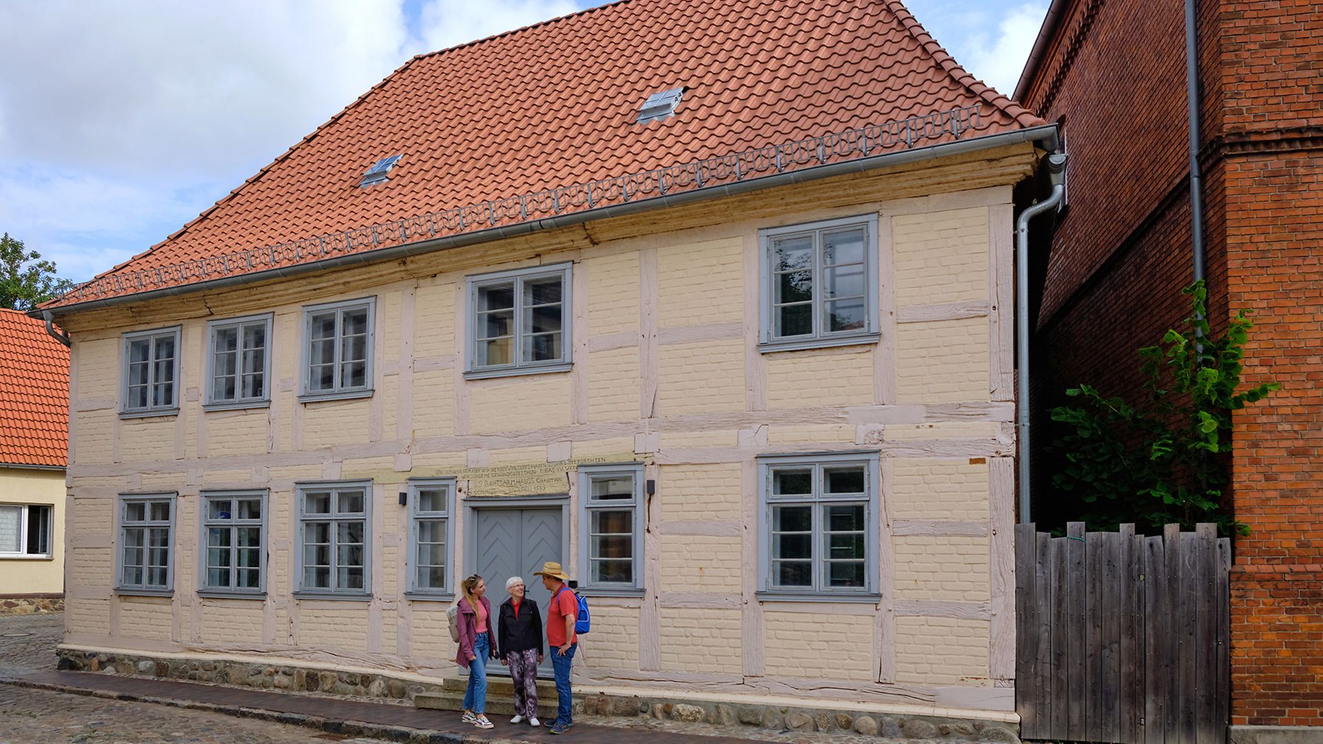 Maike, Ingo und Stadtführerin Edith vor einem Haus in der Bützower Altstadt