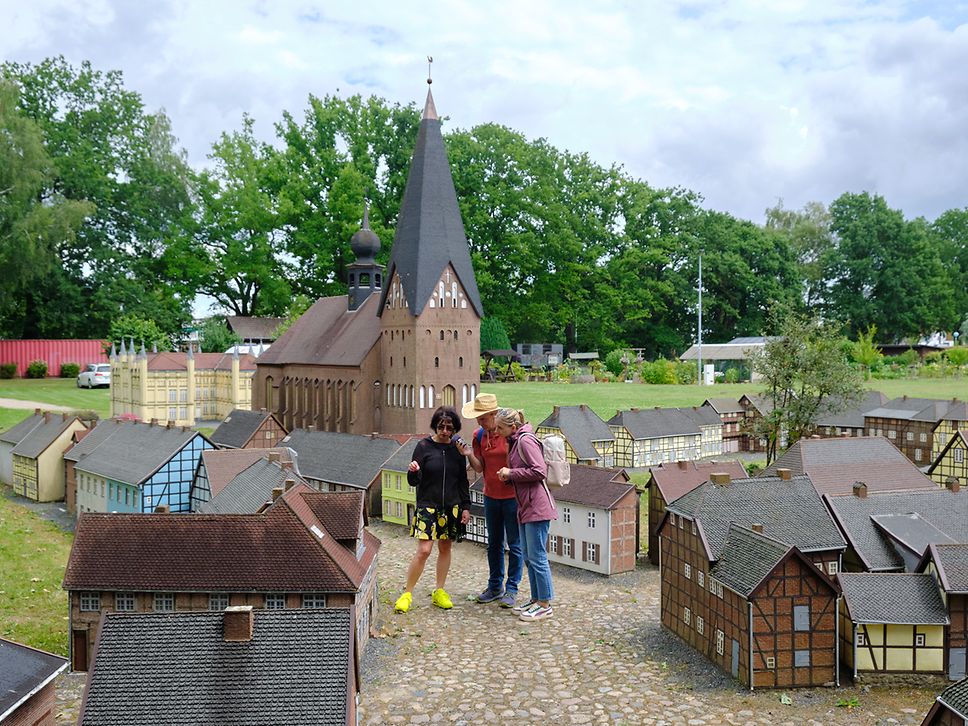 Drei Menschen überragen die Häuser der Miniaturstadt Bützow, im Hintergrund die sieben Meter hohe Mini-Stiftskirche